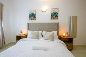 une chambre avec un grand lit blanc avec deux tables de nuit dans l'établissement Serene Spaces Garden Estate, à Gatunga