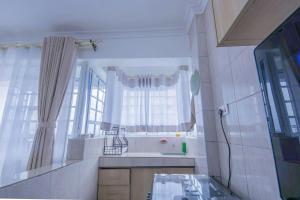 La salle de bains est pourvue d'un lavabo et d'une fenêtre avec des rideaux. dans l'établissement Serene Spaces Garden Estate, à Gatunga