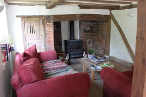 a living room with a red couch and a fireplace at B&B South Downs Way in Poynings