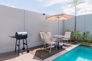 Un patio con parrilla y mesa junto a una piscina. en VINS Boutique Villa Batu, en Batu