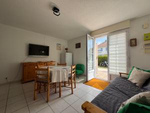 a living room with a dining room table and a television at L'Eclipse in Fort-Mahon-Plage