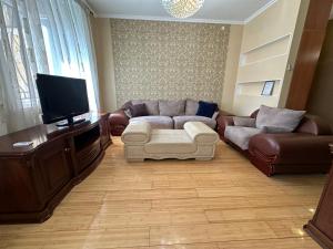 a living room with a couch and a flat screen tv at Апартаменты на Назарбаева 44 in Karagandy