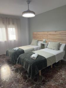 a room with three beds with green and white sheets at La Roca in Losa del Obispo
