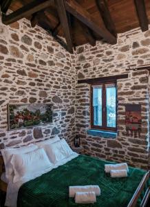 a bedroom with a bed in a stone wall at Αρχοντικό Πανόραμα in Melívoia