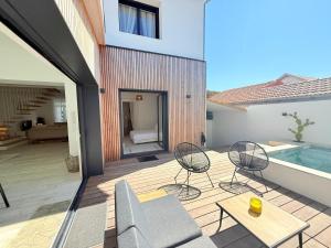 eine Terrasse mit zwei Stühlen und einem Swimmingpool in der Unterkunft Villa NORMANDY in Saint-Georges-de-Didonne