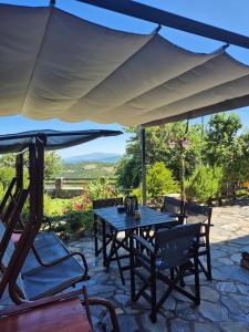 a table and chairs under an umbrella on a patio at Αρχοντικό Πανόραμα in Melívoia +48 photos