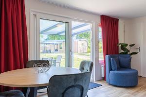 a dining room with red curtains and a table and chairs at Welcome in - Chalet Bosdier, Camping de Duinhoeve Burgh-Haamstede in Burgh Haamstede