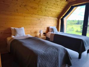 two beds in a log cabin with a window at Przystań Szwecja in Szwecja