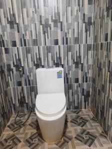 a bathroom with a white toilet in a tile wall at Joes Homestay in Siem Reap