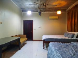 a room with two beds and a table and a door at Joes Homestay in Siem Reap