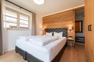 a bedroom with a large white bed with a wooden wall at Penthouse No9 in Oberstaufen