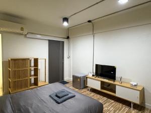 una camera da letto con un letto e una TV a schermo piatto di The beeroom by BoonmeeApt a Sathani Sam Sen