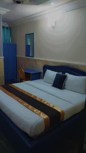 a bedroom with a large bed with a blue headboard at Camzy Villa Hotel in Abuja