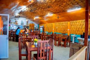 ein Restaurant mit Holztischen und -stühlen und Menschen im Hintergrund in der Unterkunft Golden Beach Hotel & Restaurant in Trincomalee