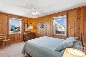 - une chambre avec des murs en bois, un lit et deux fenêtres dans l'établissement 6137 - Harper, à Nags Head