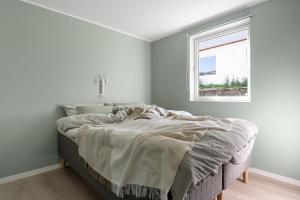 ein unmaskiertes Bett in einem weißen Zimmer mit einem Fenster in der Unterkunft Northstay - Tromsø Urban Retreat - Free Parking, Brand New & Modern in Tromsø