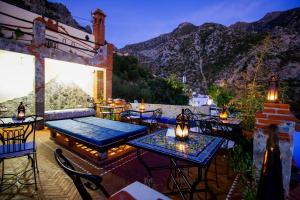 Eine Terrasse mit Tischen und Stühlen vor dem Hintergrund der Berge in der Unterkunft Riad Bab Mahrouk in Chefchaouen