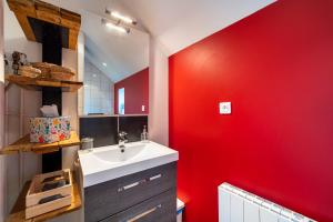 a bathroom with a sink and a red wall at Le Petit Sondebois in Saint-Gervais-en-Vallière