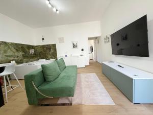a living room with a green couch and a tv at Sunset Garden in Porto Cesareo
