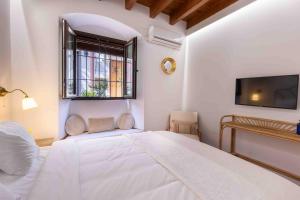 a white bedroom with a bed and a window at La Morada Mas Hermosa in Marbella
