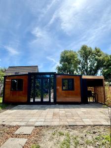 a small house with glass doors on a patio at Tiny House de Zeeuwsche Tuinkamer in Meliskerke
