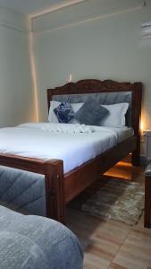 a wooden bed with white sheets and pillows in a room at Haven Studio in Ongata Rongai 
