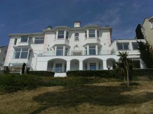 Una gran casa blanca con una palmera delante de ella. en Riviera Apartment, en Torquay