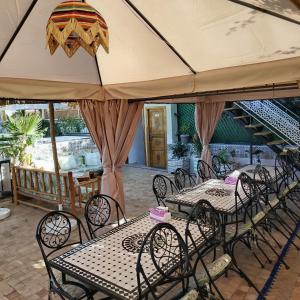 un groupe de tables et de chaises sous un grand parapluie dans l'établissement RIAD & SPA SOUS LE SOLEIL CHEZ Jérôme & Paméla, à Marrakech
