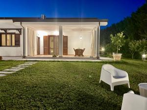 a lawn with a white chair in front of a house at La Segreta in Marina di Casalvelino