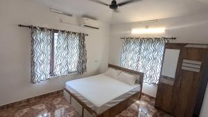 a small room with a bed and two windows at Lush Lagoon Homestay in Ambalavayal +3 photos