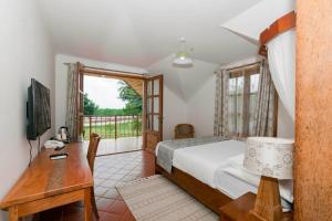 a bedroom with a bed and a desk and a window at Solomon Beach Hotel, Bagamoyo in Bagamoyo
