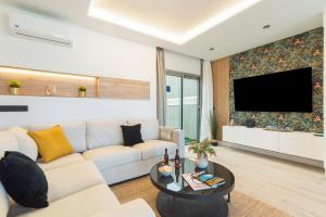 Una sala de estar con un sofá y un televisor. en Home2Book Stylish Beachfront Escape, en Arinaga