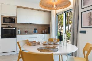 Una cocina y un comedor con una mesa y sillas blancas. en Home2Book Stylish Beachfront Escape, en Arinaga