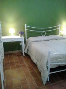 a bedroom with a white bed and a green wall at Agriturismo Camera dei ladri in Marsiliana