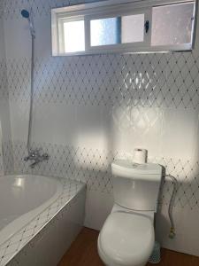 a white bathroom with a toilet and a tub at Ramachi Apartment A in Livingstone +1 photo