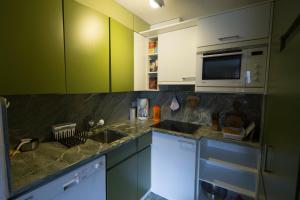 eine Küche mit grünen Schränken, einer Spüle und einer Mikrowelle in der Unterkunft Chesa Mutaun in Silvaplana