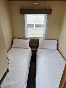 巴德利索尔特顿Elms Caravan with sea views at Devon Cliffs的一间带窗户的小房间里有两张床