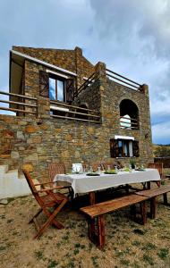 Una casa de piedra con una mesa y sillas delante de ella. en Villa Toscana, en Gökçeada