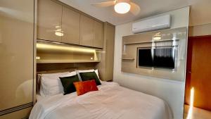 a small bedroom with a white bed and a tv at PRAIA Mar Sofisticado Novo in Vila Velha