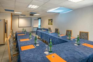 a conference room with blue tables with green bottles at Hôtel-Restaurant Le Calice Du Gevaudan - A75 in Banassac