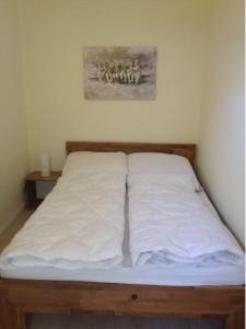 ein Bett mit weißer Bettwäsche auf einem Zimmer in der Unterkunft Ferienwohnung Kati in Zinnowitz