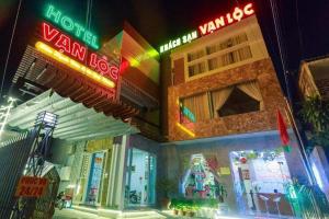 a group of buildings with neon signs at night at VẠN LỘC HOTEL in Can Tho
