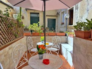 a patio with a table and chairs and an umbrella at Case Triscele - B&B in Siracusa
