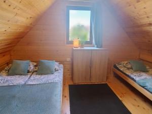 two beds in a wooden room with a window at Domki Bursztynowa Zatoka 2 in Sarbinowo