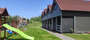 a playground next to a building with a slide at Domki Bursztynowa Zatoka 2 in Sarbinowo