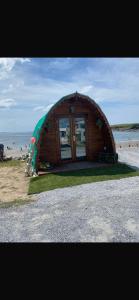 a small wooden house on the beach with the ocean at Glamping Pod in Miltown Malbay