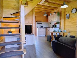 a living room and kitchen with a spiral staircase in a cabin at Domki Bursztynowa Zatoka 2 in Sarbinowo