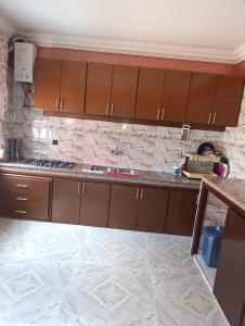 a kitchen with wooden cabinets and a marble floor at فيلا بمولاي بوسلهام in Kenitra