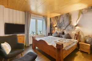 Un dormitorio con una cama, un televisor y una silla. en Ferienwohnung Haus Luise, en Olsberg