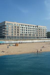 a large building on the beach with people in the water at Luksusowy apartament 431 Baltic Spa in Międzyzdroje +22 photos